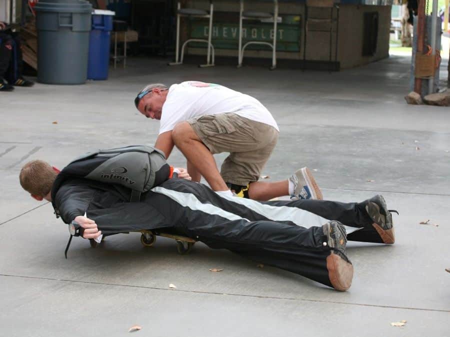 An instructor coaching a wingsuit student down on his chest wearing a black wingsuit. The context suggests a wingsuit flying course.