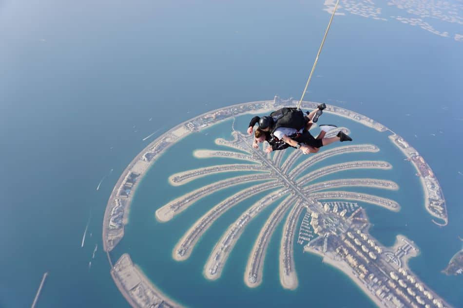 A skydiving tandem pair above a palm-shaped artificial island in Dubai called Palm Jumeirah, and it is one of the most iconic landmarks of Dubai.